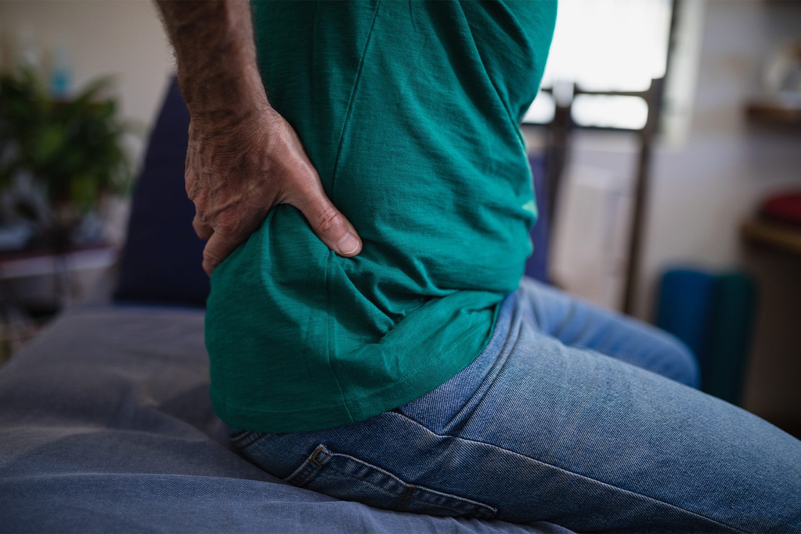 A man sitting on top of his bed with his hands behind him.